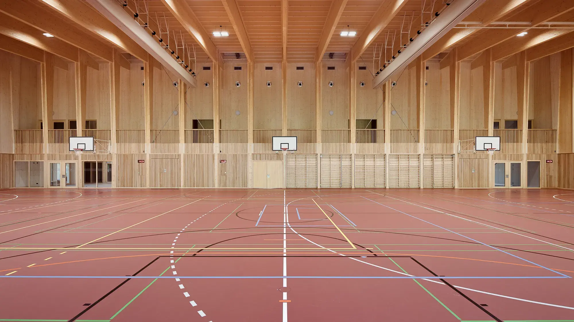 Aussenansicht der Doppelturnhalle Feltschen mit Holzfassade vor der Schulanlage
